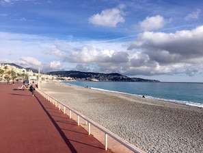 A beach with a red walkway and white railings, leading to the sea.