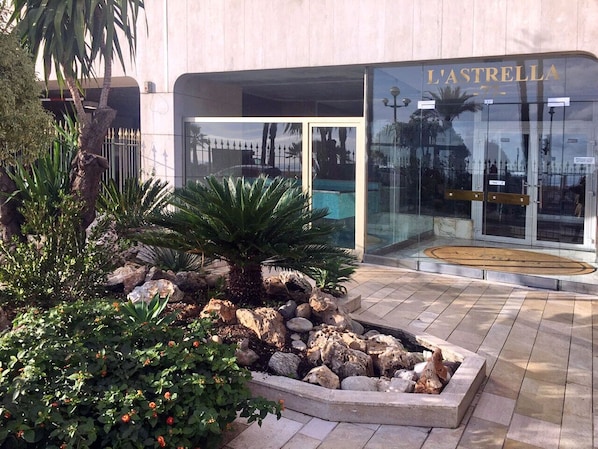 A modern building with a glass facade and the name 'L'ASTRELLA' visible.