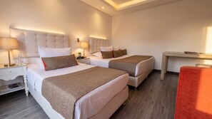 A hotel room with two beds, a nightstand, a lamp, a small table, and a red chair. - Hotel Boutique Palacete (Bogotá)