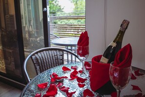 Une table avec une bouteille de champagne et deux verres, tous deux accompagnés de serviettes rouges, le tout entouré de pétales de rose.