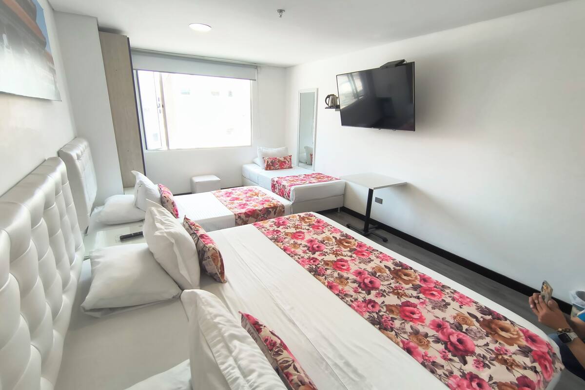 A hotel room with two beds, a TV, a window, and a small table.