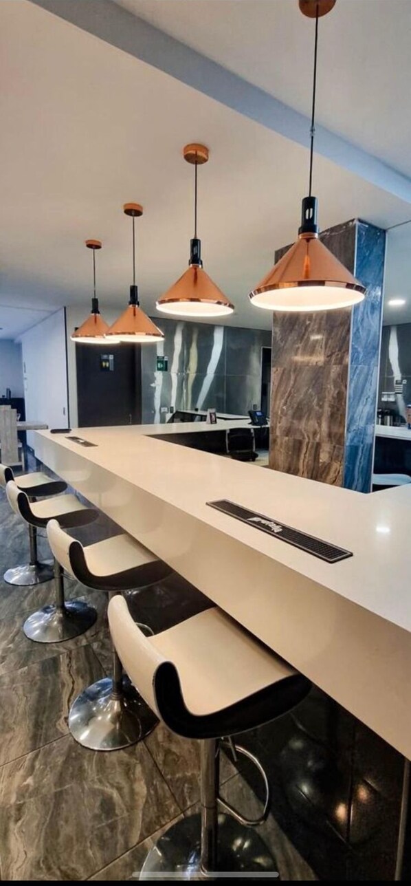 A modern kitchen with a long counter, bar stools, and pendant lighting.