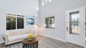Un salon spacieux avec un canapé de couleur claire, une table basse ronde en bois et un tableau accroché au mur.