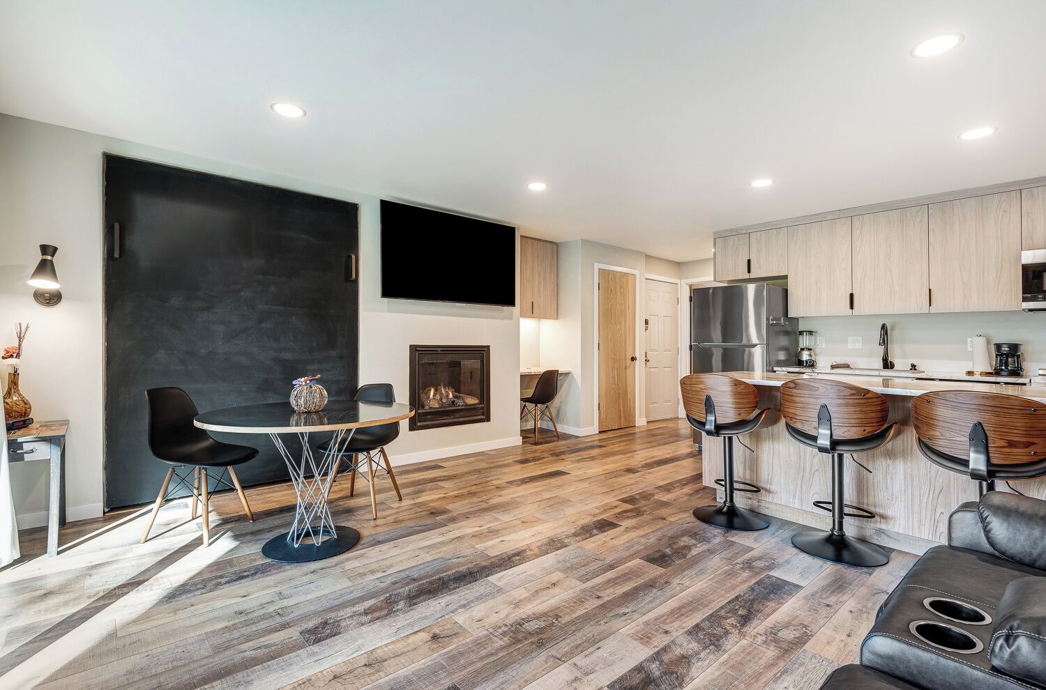 A modern kitchen with wooden cabinets, a large island with bar stools, and a dining area with a round table and chairs.