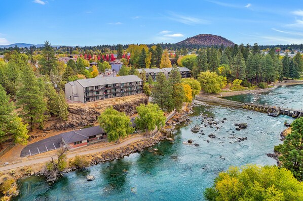 A riverside hotel with a parking area, a dock, and a view of the surrounding forest and mountains.