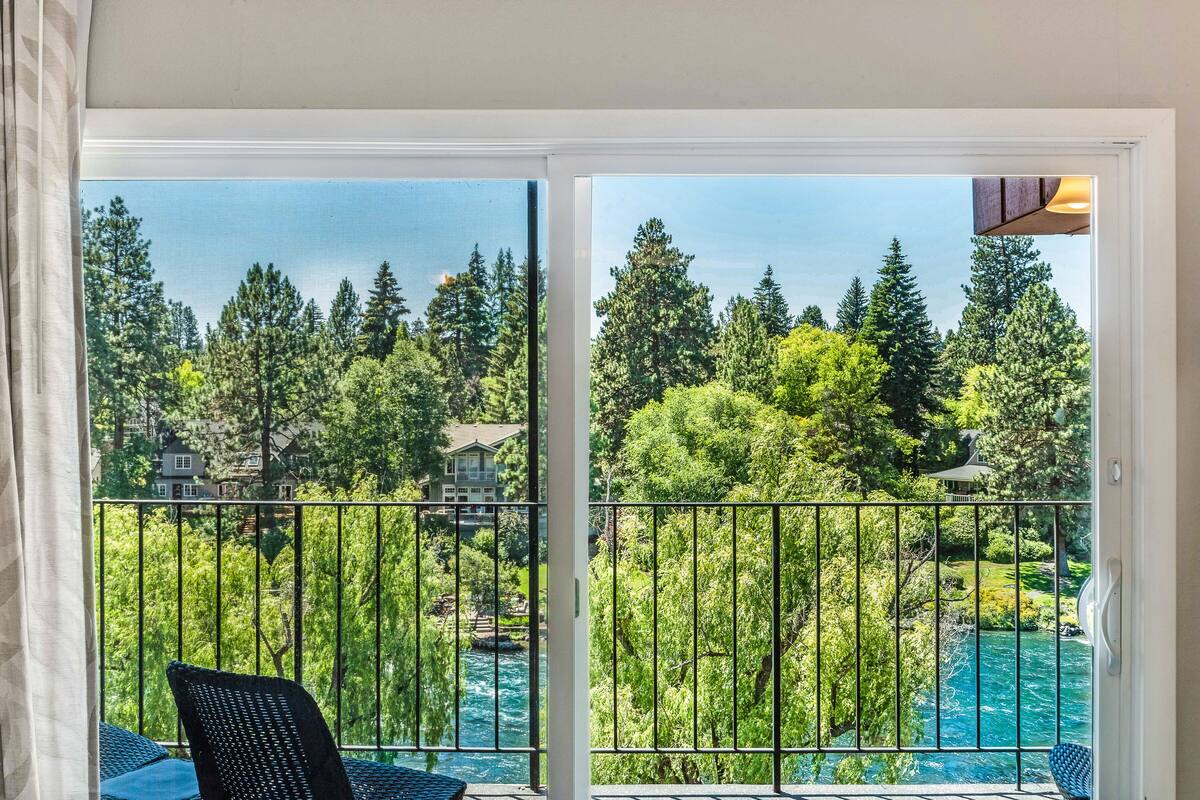 A balcony with a view of a river and forest.