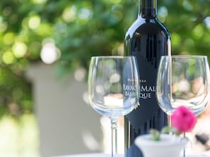 A wine bottle and two glasses on a table with a blurred green background. - Apartments Gaura - One-bedroom Apartment With Terrace (Dubrovnik)