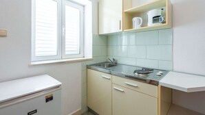 A compact kitchen with a window, a built-in sink, and a small refrigerator. - Apartments Lucija - One Bedroom Apartment With Terrace (Dubrovnik)