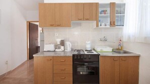Una cucina funzionale con mobili in legno, un fornello a gas, un forno e un piano di lavoro con una macchina da caffè e un bollitore.