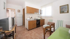 Una cucina compatta con mobili in legno, un frigorifero e un'area pranzo con un tavolo verde e sedie a righe.