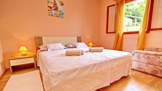 A bedroom with a large bed, two bedside tables with lamps, a chair, and a window with curtains. - Apartments Bacic - One Bedroom Apartment With Terrace and Sea View (Blato)