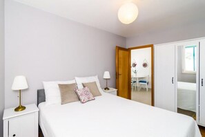 A bedroom with a bed, nightstands, a wardrobe, and a door leading to a bathroom.