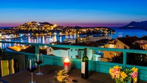 A terrace with a table set for two, a bottle of wine, and a candle. - Apartment Radovan - One-bedroom Apartment With Balcony and Sea View (Dubrovnik)