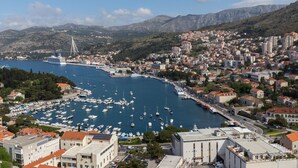A coastal town with a marina filled with boats, a prominent bridge, and a mix of residential and commercial buildings. - Apartment Super Marijo - Two-bedroom Apartment With Sea View (Dubrovnik)
