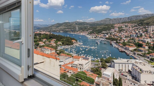 A coastal cityscape with a marina filled with boats, surrounded by residential buildings and hills. - Apartment Super Marijo - Two-bedroom Apartment With Sea View (Dubrovnik)