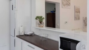 A modern kitchen with white cabinetry, a microwave, a toaster, and a potted plant on the counter. - Apartment Super Marijo - Two-bedroom Apartment With Sea View (Dubrovnik)