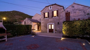 A stone building with a central door and windows, surrounded by a paved area with hexagonal tiles. - Villa Nives - Three-bedroom Villa With Terrace and Sea View (Ston)