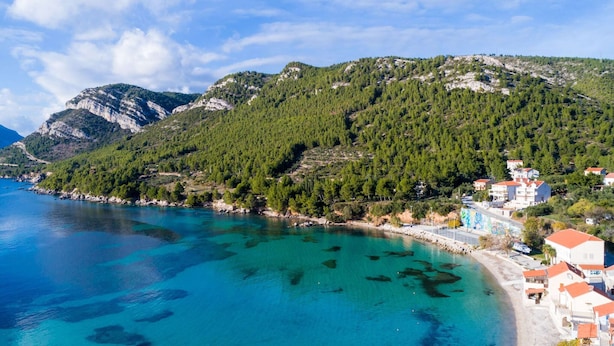 A coastal town with a clear blue sea, a mountainous backdrop, and buildings with red roofs. - Villa Nives - Three-bedroom Villa With Terrace and Sea View (Ston)