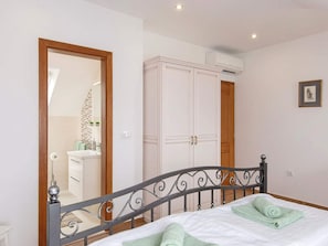 Une chambre à coucher avec un lit, une armoire et une salle de bain visible à travers une porte ouverte.