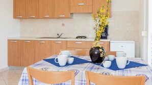 Cozinha moderna com armários de madeira, painel de azulejos e área de jantar com mesa posta para quatro.