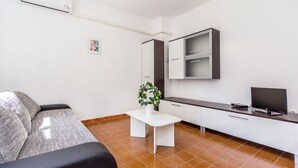 A modern living room with a sofa, a small white table with a plant, a TV, and a mirror on the wall. - Apartment With Terrace and Pet-friendly (Medulin)