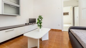 A modern hotel room with a white desk, a flat-screen TV, a potted plant, and a bed. - Apartment With Terrace and Pet-friendly (Medulin)