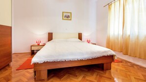A bedroom with a wooden bed, a nightstand, a lamp, and a window with curtains. - Apartment With Terrace and Pet-friendly (Medulin)
