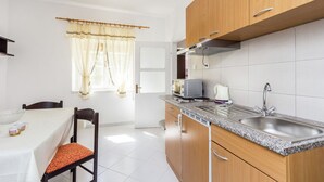 A compact kitchen with wooden cabinets, a granite countertop, a sink, and a window with curtains. - Apartment With Terrace and Pet-friendly (Medulin)