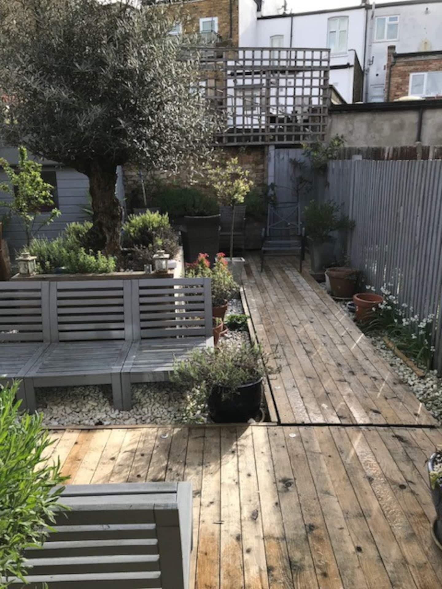 A wooden deck with a bench and potted plants.