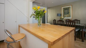 A kitchen with a wooden island, a chair, and a vase with flowers. - Stunning 3 Bedroom House With Garden in Battersea (London)