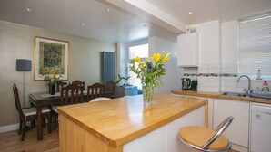 A modern kitchen with a wooden island, white cabinets, and a sink. - Stunning 3 Bedroom House With Garden in Battersea (London)