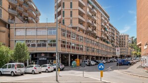 A multi-story residential building with balconies, a street view, parked cars, and a clear sky. - Apartment in Rome With Balcony (Rome)