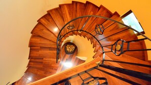 A wooden spiral staircase with a metal handrail and a small decorative element at the top.