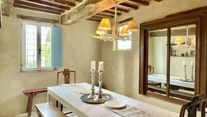 A dining area with a long table, benches, candles, and a chandelier.