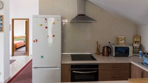A compact kitchen with a refrigerator, stove, microwave, and oven.