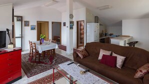 A compact living space with a dining area, a sofa, a kitchen, and a TV.