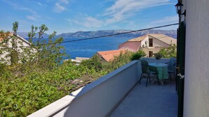 A balcony with a view of the sea and mountains, a table with chairs, and a lamp. - Guest House Hazdovac Rooms - Two Bedroom Apartment With Terrace and Sea View (Mljet)