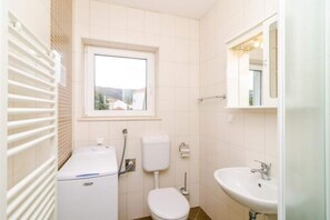 Une petite salle de bain propre, équipée de toilettes, d’un lavabo et d’une fenêtre.