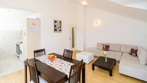 A modern living room with a dining table, sofa, and coffee table. - Apartments Nikola - One Bedroom Apartment With two Balconies and Sea View (Dubrovnik)
