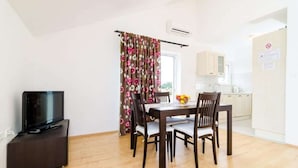 A compact living space with a dining area, a kitchenette, and a television on a stand. - Apartments Nikola - One Bedroom Apartment With two Balconies and Sea View (Dubrovnik)