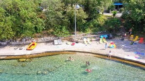 A clear swimming pool surrounded by a pebble beach with lounge chairs and inflatable toys. - Apartment Bay Of Dreams - Two-bedroom Apartment With Terrace and Sea View (Janjina)