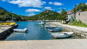 A coastal marina with several small boats docked, a clear blue sky, and a mountainous backdrop. - Apartment Bay Of Dreams - Two-bedroom Apartment With Terrace and Sea View (Janjina)
