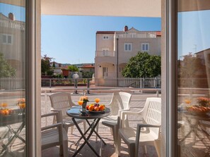 En balkon med et bord dækket til to personer, med en skål frugt og to glas appelsinjuice.