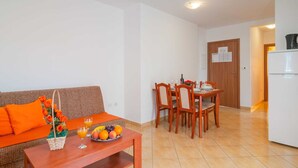 Een knus woongedeelte met een bank, eettafel, stoelen en een kitchenette.