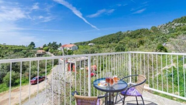 A balcony with a table and chairs, overlooking a road and greenery. - Apartments Dalamar - Three-bedroom Apartment With Terrace (Mljet)