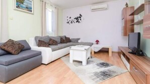 A modern living room with a grey sofa, a white coffee table, and a wooden TV stand. - Apartments Dalamar - Three-bedroom Apartment With Terrace (Mljet)
