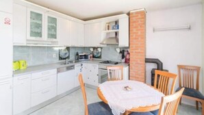 A compact kitchen with white cabinets, a dining table with a lace tablecloth, and a brick column. - Apartments Dalamar - Three-bedroom Apartment With Terrace (Mljet)