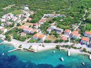 An aerial view of a coastal residential area with houses, a beach, and clear blue waters. - Apartments Marko Peljesac - Two Bedroom Apartment With Balcony (Orebic)