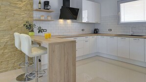 A modern kitchen with white cabinets, a wooden countertop, and a stone accent wall. - Family Villa With Swimming Pool (Liznjan)