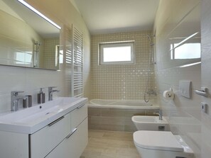 A modern bathroom with a white vanity, a bathtub, and a toilet. - Apartment in Croatia Near the Beach (Liznjan)